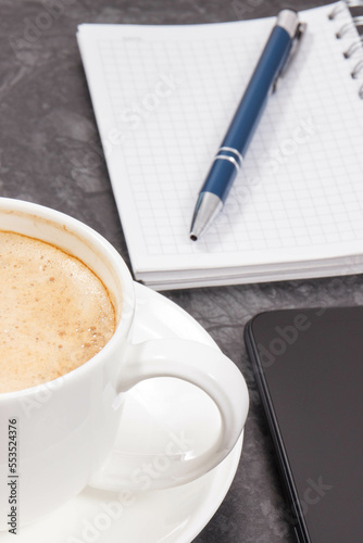 Mobile phone, coffee with milk and notepad for writing notes. Work or relaxation