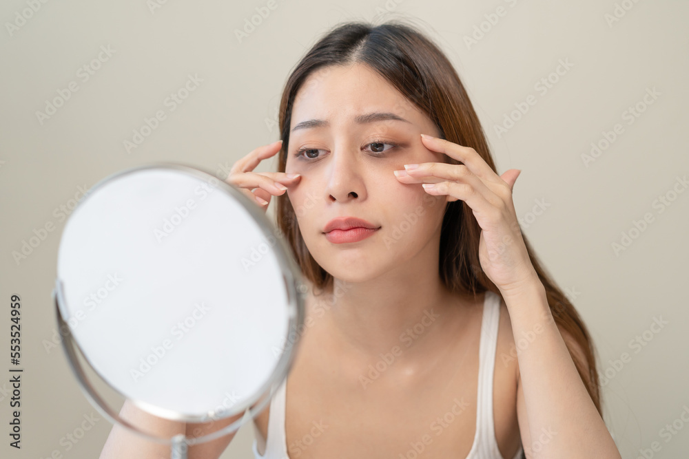 lack of sleep problem, Worried Asian young woman pointing finger at dark circles under her eyes lack of sleep problem, Worried Asian young woman pointing finger at dark circles under her eyes