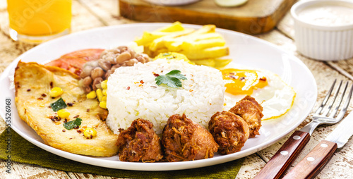 plate of rice and beans typical of Brazil, fried sausage, fried egg, chopped vegetables and salad, brazilian restaurant food
