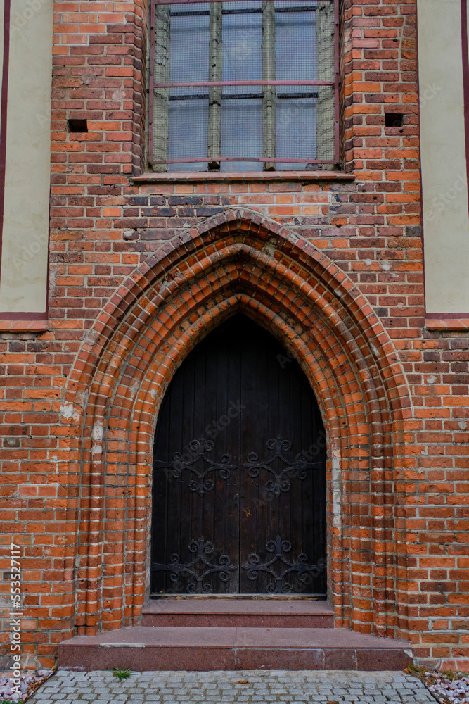Old Gothic wooden door in brick building.