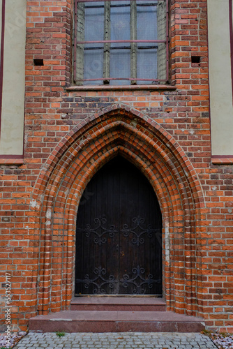 Old Gothic wooden door in brick building.