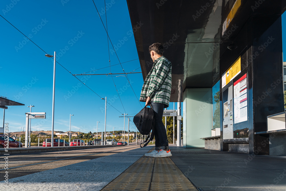 Male student waiting for the tram