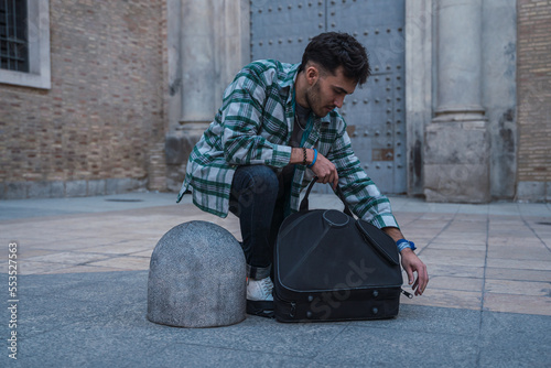 Obraz na płótnie Male musician opening his suitcase on the street to start playing his horn. w salonie