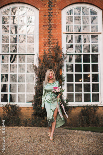 Blonde happy woman in dress  holding big bouquet flowers. blooming flowers, pastel and soft bouquet floral card.