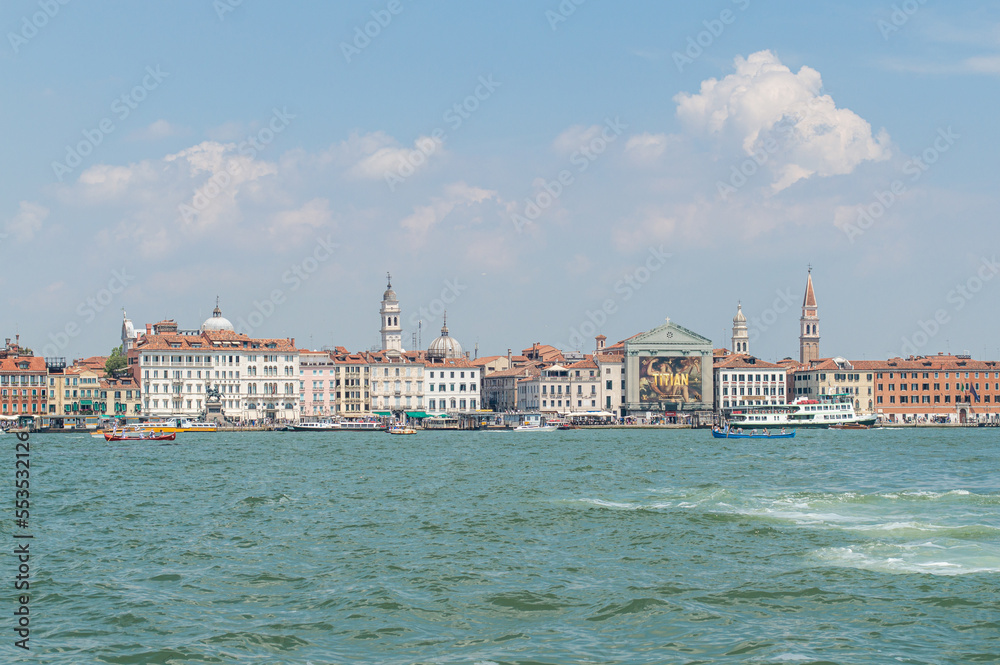 View of the Venice Canal embankment on a warm summer day, with floating boats and old houses, Venice, Italy