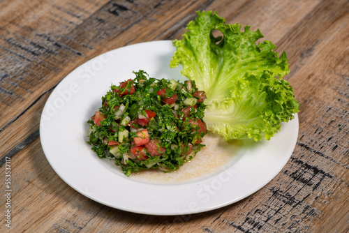 Dish of Middle-Eastern Tabbouleh salad with lettuce on white background. High quality photo
