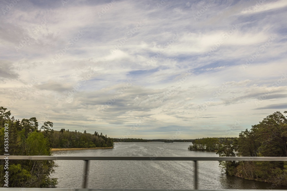 Beautiful landscape view of large lake with forest trees from window of passing car over bridge. Sweden.