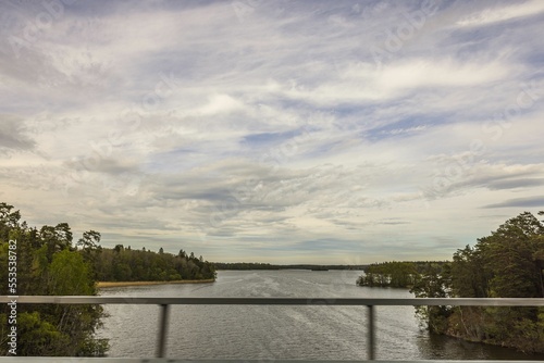 Beautiful landscape view of large lake with forest trees from window of passing car over bridge. Sweden. © Alex