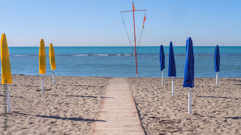 wooden path on the sandy beach leading to the sea against the blue sky