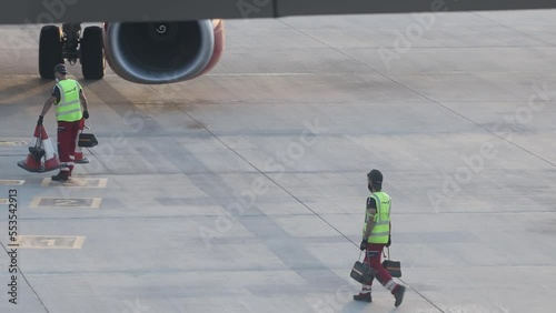 Larnaca, Cyprus. May 15, 2021: The airport staff is engaged in the reception and maintenance of a passenger aircraft, placing fencing cones photo