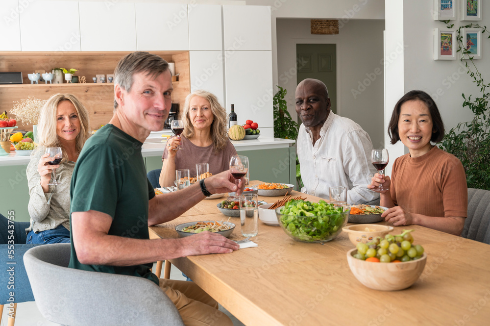 Group of diverse senior friends gathered together for lunch in the kitchen Group of diverse senior friends gathered together for lunch in the kitchen