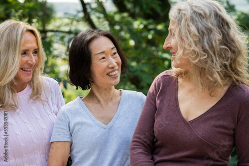 Three middle aged women having a friendly conversation in their backyard