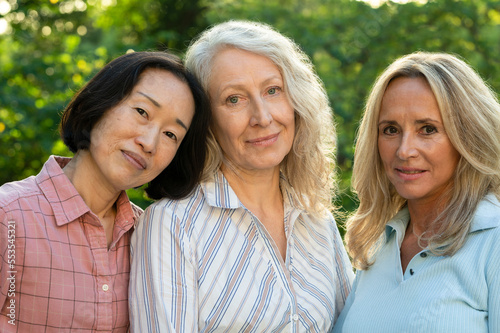 Group of three middle-aged women posing for photo in backyard