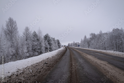 wet snow and mud covered asphalt road near Jelgava town  Latvia. Beautiful moody overcast winter day in December.
