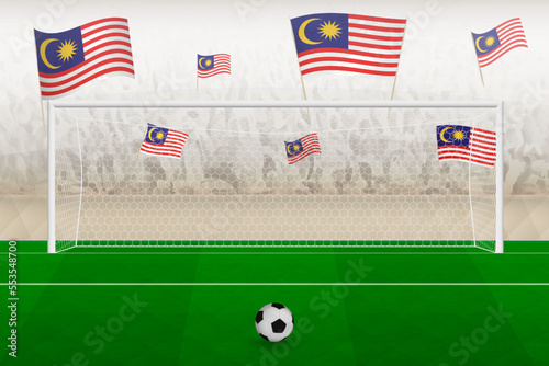 Malaysia football team fans with flags of Malaysia cheering on stadium, penalty kick concept in a soccer match.