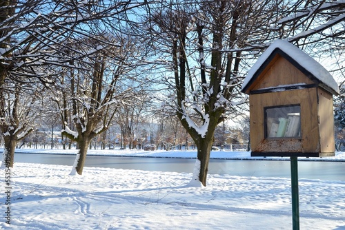 Wooden nesting box turned into free public library. Book box in snowy landscafe of castle park. Winter in Holesov castle.  © Adela