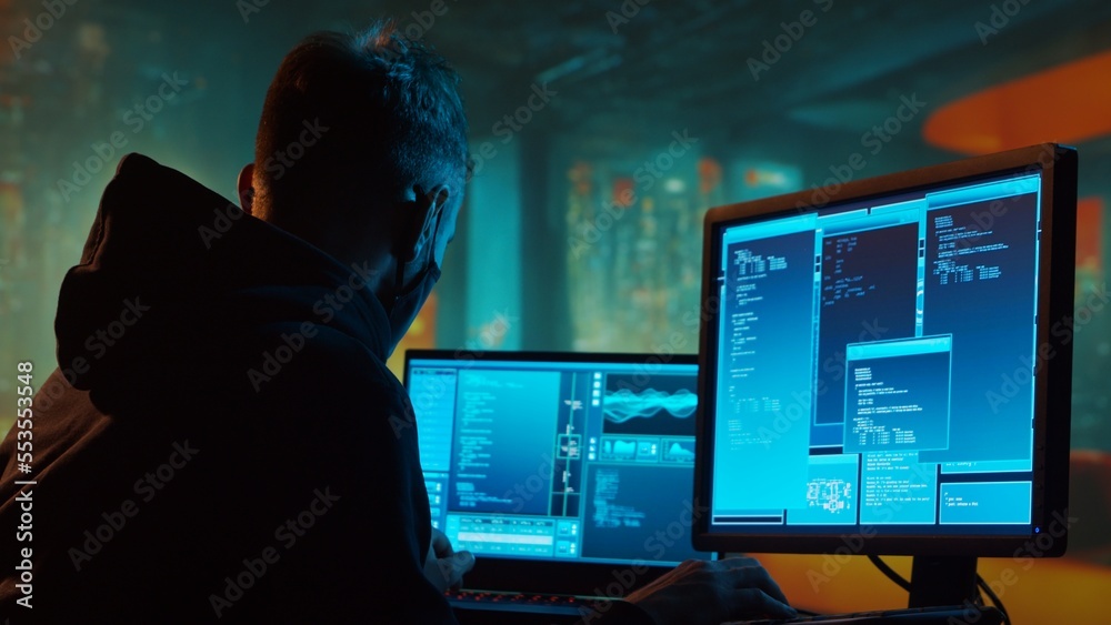 Computer Hacker in Hoodie. Obscured Dark Face. Concept of Hacker Attack, Virus Infected Software, Dark Web and Cyber Security. Computer Hacker in Hoodie. Obscured Dark Face. Concept of Hacker Attack, Virus Infected Software, Dark Web and Cyber Security.