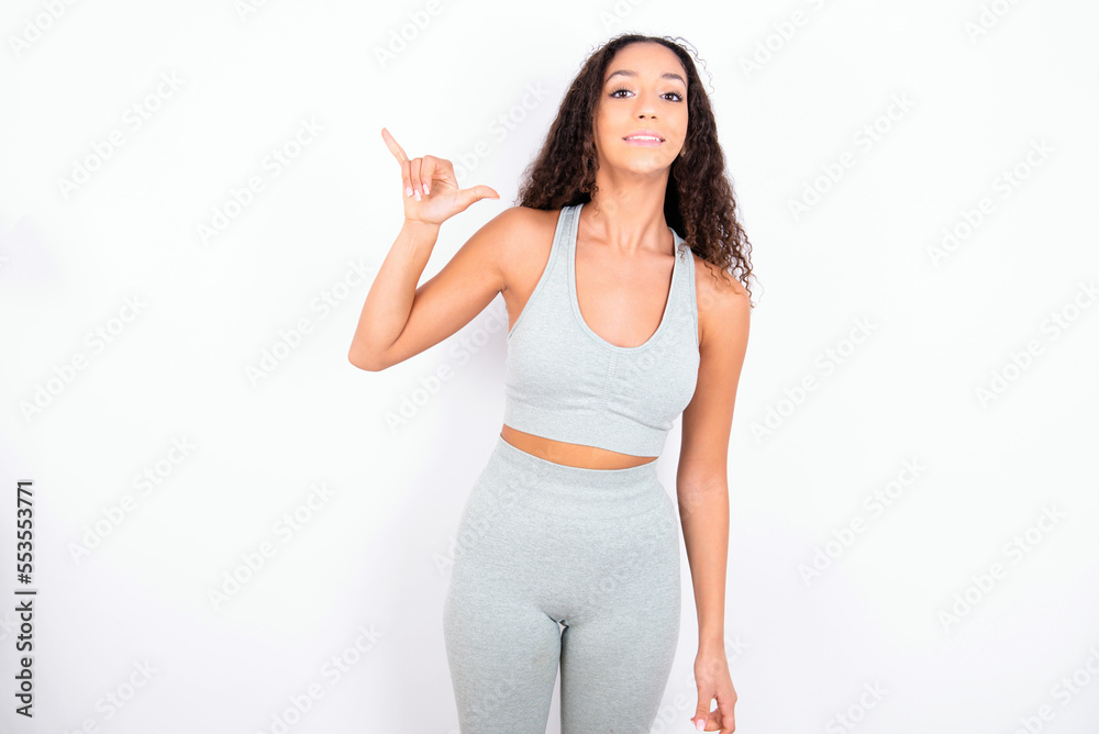 Beautiful teen girl with curly hair wearing green sport set over white background showing up number six Liu with fingers gesture in sign Chinese language Beautiful teen girl with curly hair wearing green sport set over white background showing up number six Liu with fingers gesture in sign Chinese language