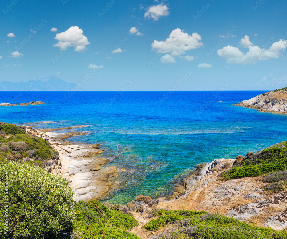 Summer stony sea coast landscape with Atthos mount view in far (Halkidiki, Sithonia, Greece).