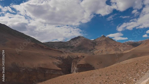 4K shot of Gorge canyon at Dry mountains of Spiti Valley with view of Chicham village. Dry rugged Himalaya mountains of Spiti, Himachal Pradesh, India. Mountains in background of blue cloudy sky. photo