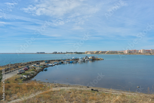 Beautiful sea view on a clear sunny day. You can see the pier with fishing boats and the city on the horizon