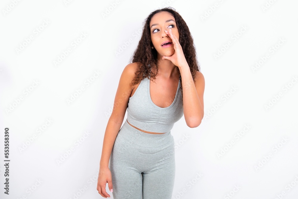teen girl with curly hair wearing white sport set over gray background hear incredible private news impressed scream share teen girl with curly hair wearing white sport set over gray background hear incredible private news impressed scream share