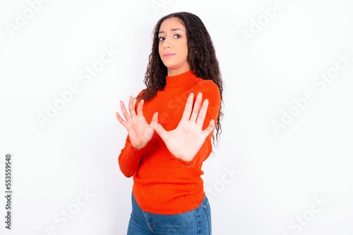 Ugh how disgusting! Displeased teen girl wearing knitted red sweater over white background , has dissatisfied facial expression as sees something abominable.