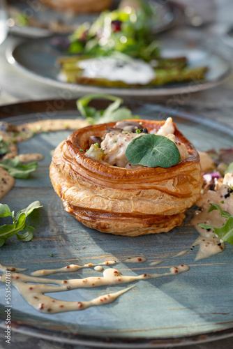 Chicken and mushroom vol-au-vent on a styled ceramic plate, delicious hot dish with hollow shells of puff pasty and creamy filling prepared and served in an elegant gourmet restaurant as a main course
