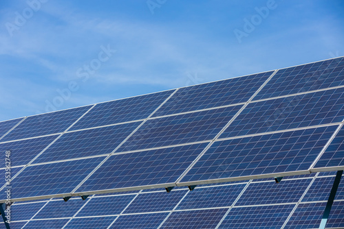 Solar cells panels. Solar farm on blue sky background. Photovoltaics solar cells panels in solar power station. Green energy from natural and Clean energy concept