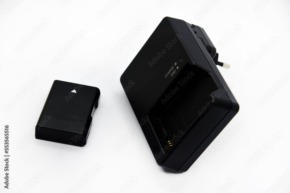 Black charger and battery for cameras. Charger and battery on a white background. Black accessories for the camera. Black charger and battery for cameras. Charger and battery on a white background. Black accessories for the camera.