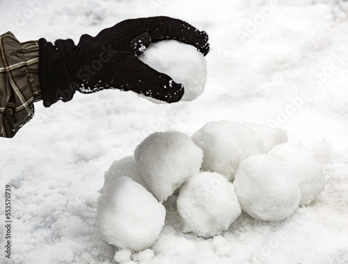 A gloved hand making a pile of snowballs for a snowball fight; Fairmont, Alberta, Canada