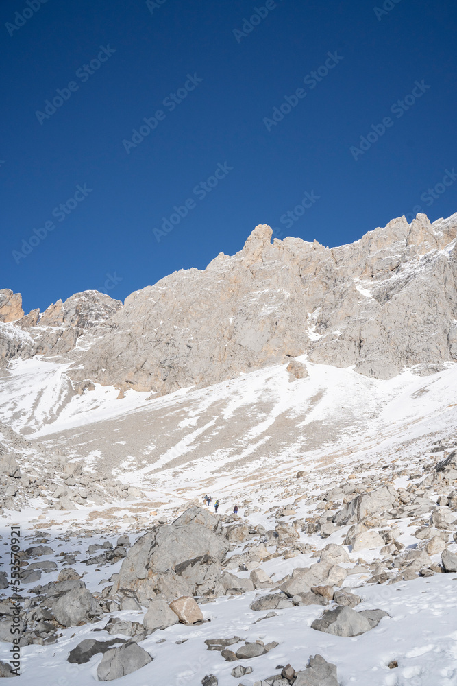three alpinists clibing a snowy mountain in winter