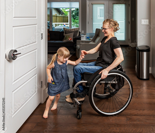 A paraplegic mother dancing with her daughter in the kitchen using her whellchair: Edmonton, Alberta, Canada photo