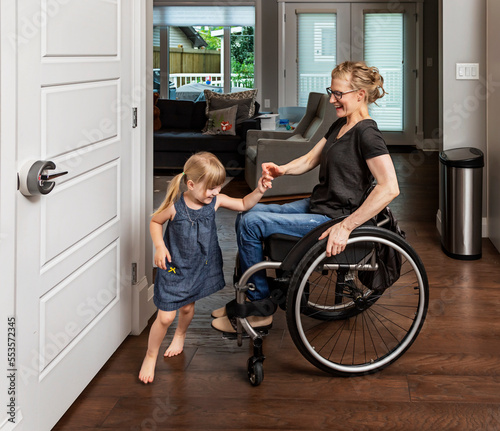 A paraplegic mother dancing with her daughter in the kitchen using her whellchair: Edmonton, Alberta, Canada
