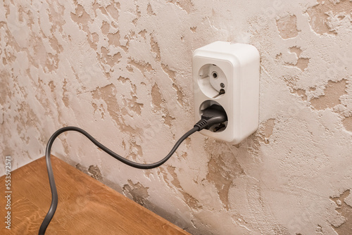 Plug in a double outlet on a white plaster background in a modern room interior