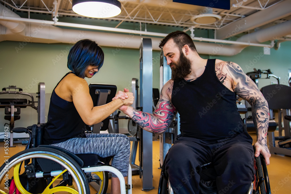 Two paraplegic friends pretending to arm wrestle after working out at a