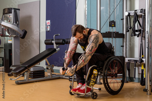 A paraplegic man working out using a crossover pulley weight lifting apparatus in a fitness facility; Sherwood Park, Alberta, Canada photo