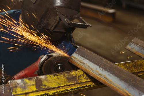 Tradesman grinding a steel beam in a metal fabrication plant; Innisfail, Alberta, Canada photo