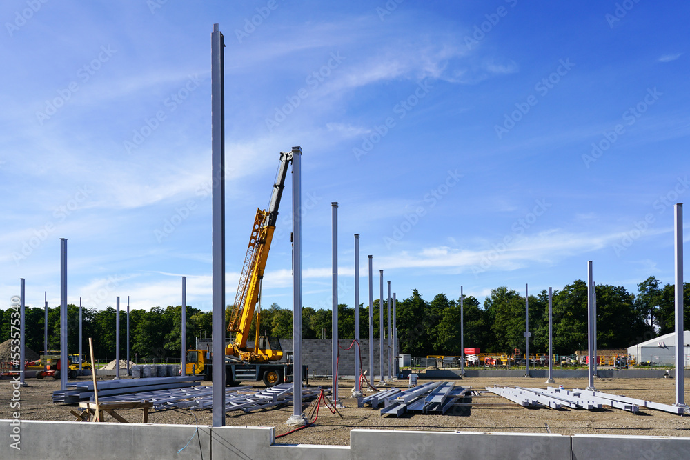 Construction site of a new industrial building with vertical steel columns and a telescopic crane Construction site of a new industrial building with vertical steel columns and a telescopic crane
