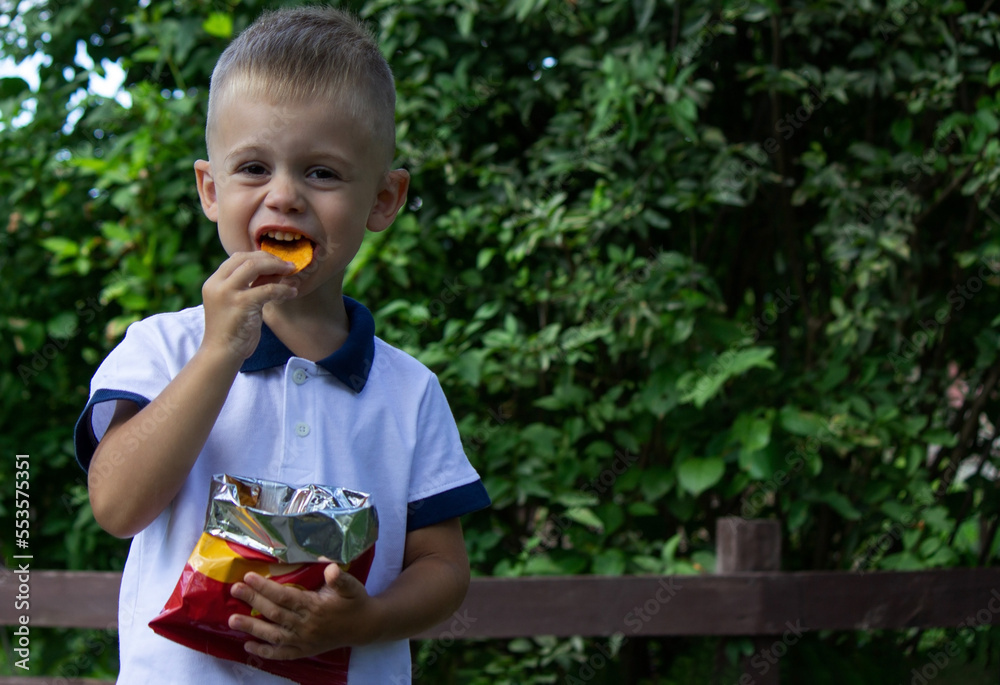 little boy eats potato chips from a pack. little boy eats potato chips from a pack.