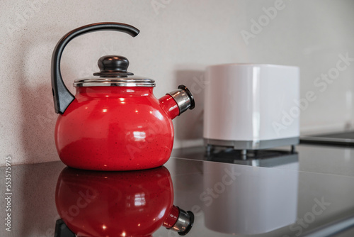 Red kettle on the stove next to the toaster