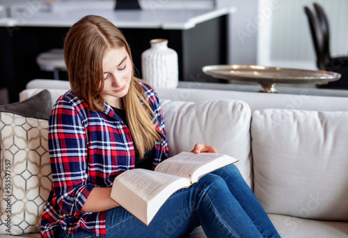 Teenage girl sitting on a couch at home and reading the Bible; Edmonton, Alberta, Canada photo
