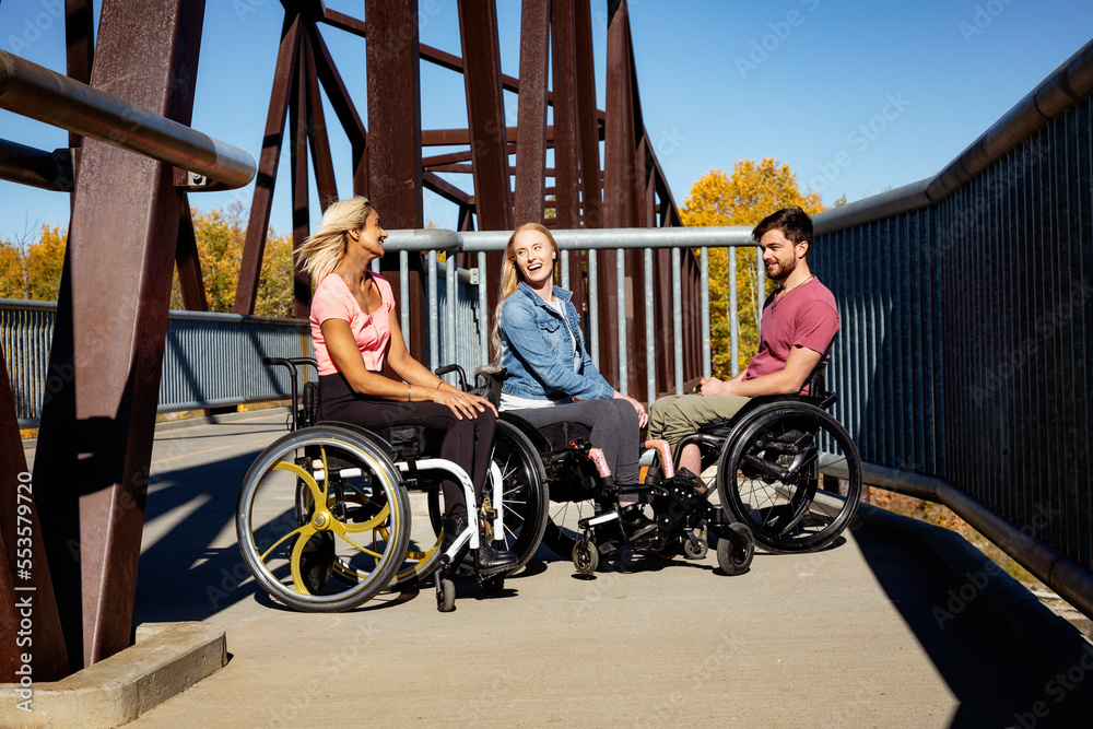 Group of three young paraplegics in their wheelchairs visiting together