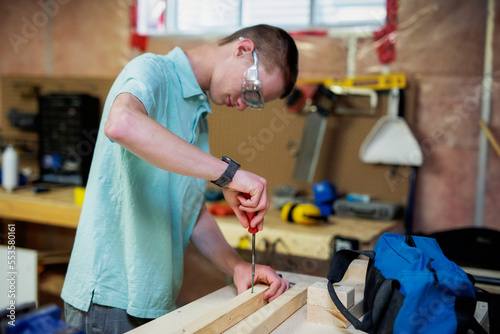 Young man doing woodworking in his basement; Edmonton, Alberta, Canada photo