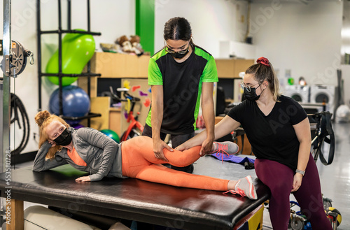 A paraplegic woman working on hip flexion while her trainer does physical queuing: Edmonton, Alberta, Canada