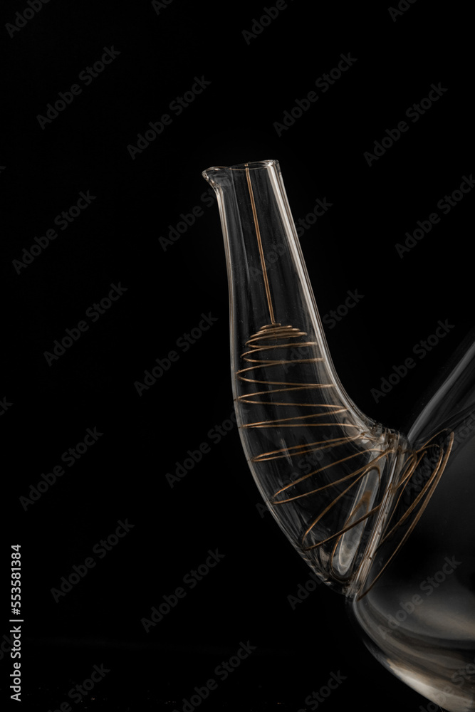Spout of beautiful transparent glass teapot close-up isolated on black background. Spout of beautiful transparent glass teapot close-up isolated on black background.