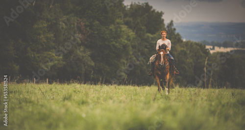 Pretty, young, redhead woman with her lovely horse, during her favorite leisure