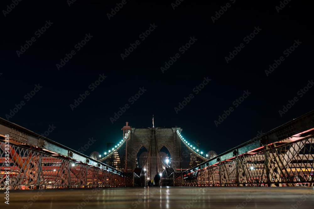 Obraz premium Brooklyn Bridge in New York at night. Skyscrapers of a large metropolis. Night city at long exposure. Towers in the big city.