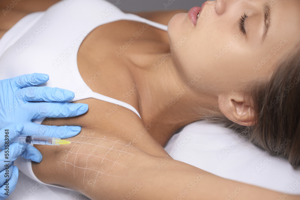 Young woman getting armpits injection in salon, closeup