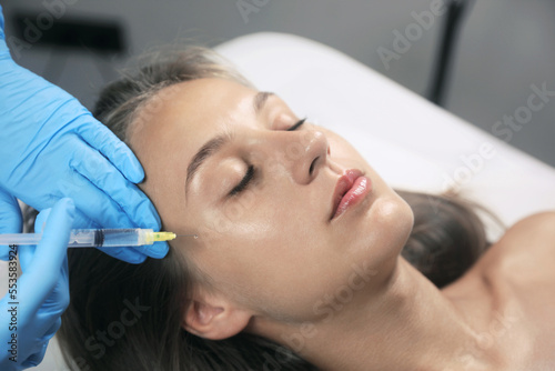 Beautiful woman getting facial injection in salon